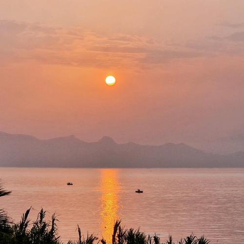 a sunset over the water with boats in it at sizilien in Trappeto