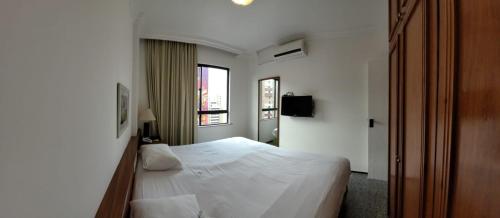 um quarto com uma cama branca e uma janela em Flat Meireles, Vista Mar, Avenida Abolição AP 1307 , 1404 em Fortaleza