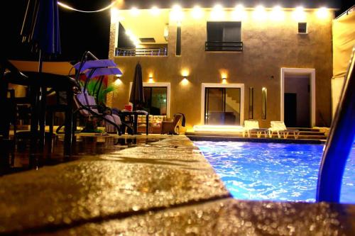 a swimming pool in front of a house at night at Celina's farm in Al Rama