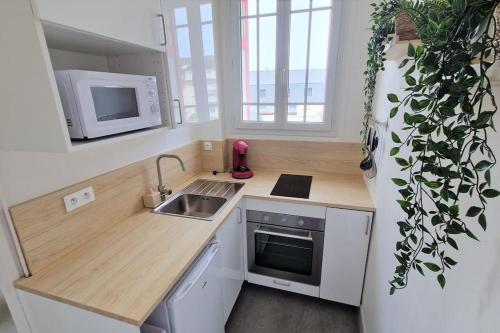 une petite cuisine avec un évier et un micro-ondes dans l'établissement Appartement Ouistreham proche centre et plage, à Ouistreham