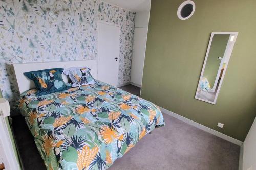 a bedroom with a bed with a colorful comforter and a mirror at Appartement Ouistreham proche centre et plage in Ouistreham