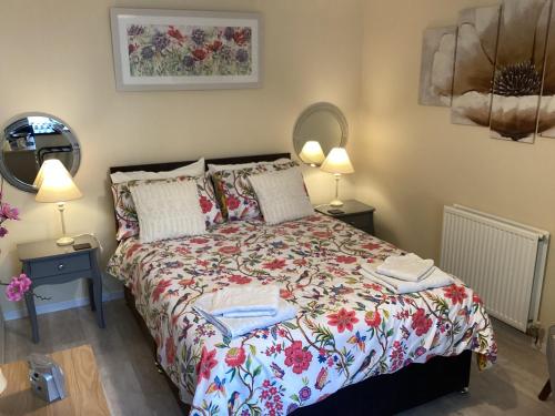1 dormitorio con 1 cama con colcha de flores en Plas Bach en Haverfordwest