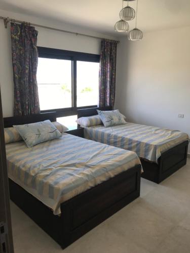 a bedroom with two beds and a window at Swanlake north coast in Zāwiyat al ‘Awwāmah