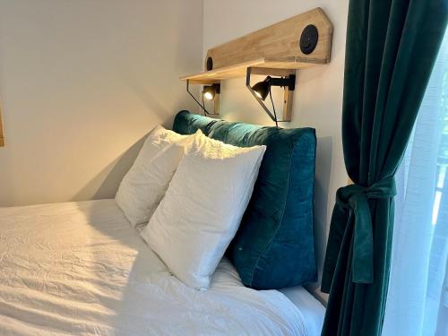 a bed with a green head board and two pillows at Somptueux studio de 17m2 Bernex in Bernex