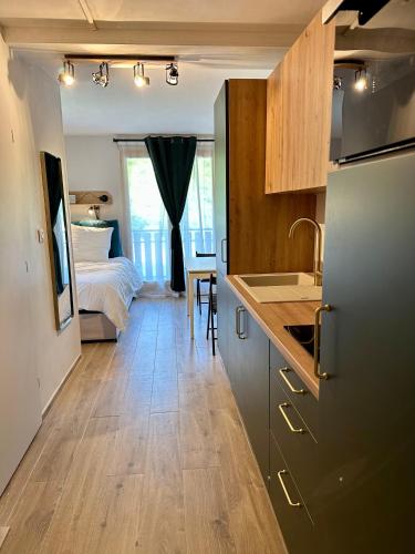 a kitchen with a refrigerator and a bedroom with a bed at Somptueux studio de 17m2 Bernex in Bernex