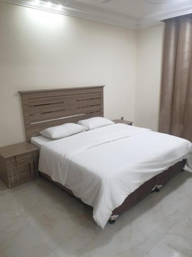 una camera da letto con un letto grande con lenzuola e cuscini bianchi di Rose Apartment a Salalah