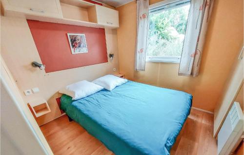 a small bedroom with a blue bed and a window at Stunning Caravan In Hyres With Wifi And 3 Bedrooms in Hyères