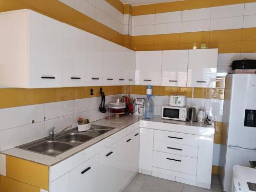 a kitchen with white cabinets and a sink at Keurgui La Maison in Gandigal