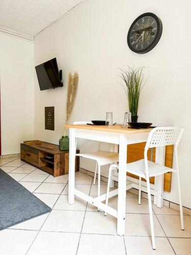 une table blanche avec des chaises et une horloge sur le mur dans l'établissement NEW ! Le Coeur de ville avec terrasse! Parking, à Guingamp