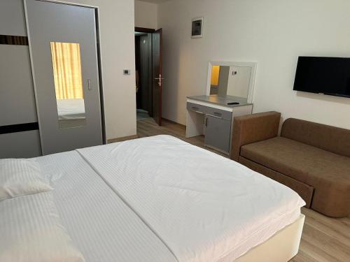 een slaapkamer met een bed, een bank en een televisie bij Vila Andrra in Struga