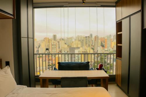 a room with a large window with a table and chairs at Belíssimo Stúdio in Sao Paulo