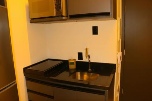 uma cozinha com um lavatório e uma bancada em Belíssimo Stúdio em São Paulo