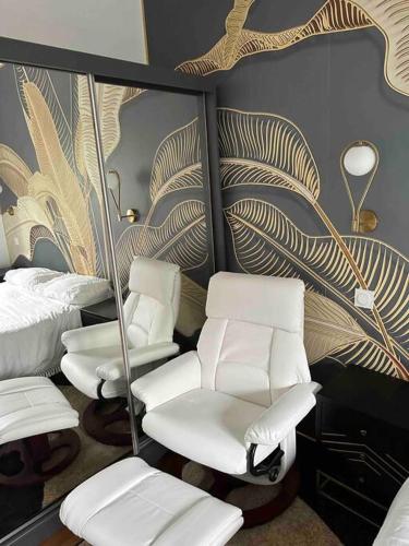 Cette chambre comprend des chaises blanches, un lit et un miroir. dans l'établissement Logement tout confort avec jardin proche centre, à Besançon