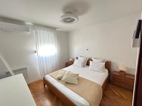 een slaapkamer met een bed met witte lakens en kussens bij Beach Apartment Lux View in Split