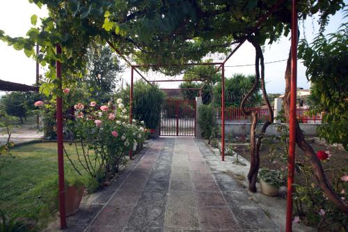 a garden with a pergola with flowers and roses at Drosia Residence in Nea Kios