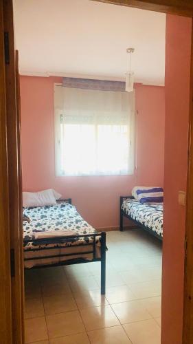 2 Betten in einem Zimmer mit Fenster in der Unterkunft Cartier El MANAR El jadida CITY in El Jadida