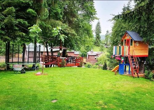 une cour avec une aire de jeux et une maison de jeux dans l'établissement Casuta dintre brazi - Valea Doftanei - 2 camere, à Valea Doftanei