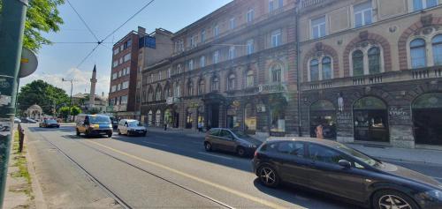 eine Straße mit Autos, die eine Stadtstraße mit Gebäuden entlangfahren in der Unterkunft Apartman Centar in Sarajevo