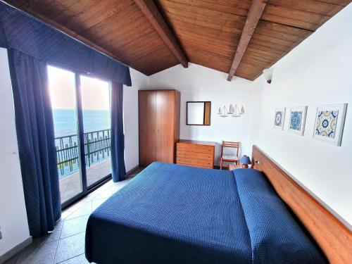a bedroom with a blue bed and a large window at Villa Anita Apartments in Capo dʼOrlando