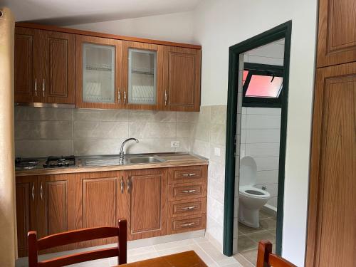una cucina con armadi in legno, lavandino e servizi igienici di Hibroj Guesthouse a Vlorë