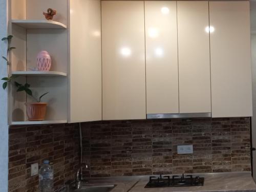 una cocina con armarios blancos y fregadero en NG Cozy App, en Tiflis