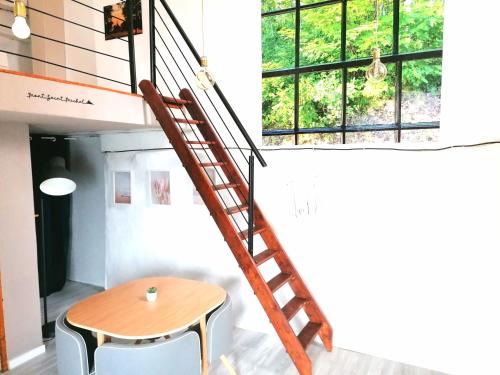 Eine Wendeltreppe führt zu einem Zimmer mit einem Tisch und einem Fenster. in der Unterkunft Charmant studio sur la route du Mont-St-Michel in Les Portes du Coglais