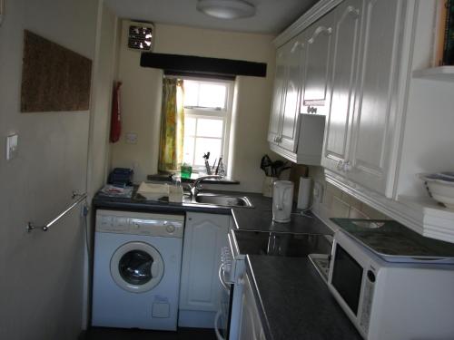 a kitchen with a washing machine and a sink at Barton Cottage in Bude