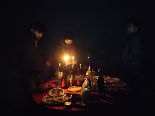 un grupo de personas de pie alrededor de una mesa con botellas y velas en Jhoomke camping and water sports adventure, en Auraiya