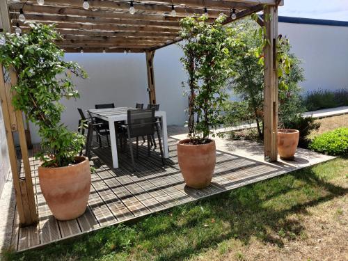 une terrasse en bois avec une table et des plantes en pot dans l'établissement Planchesdisa, à Saint-Pair-sur-Mer