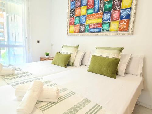 two beds in a white room with a painting on the wall at Apartamento 3 dormitorios Malaga (Teatinos) in Málaga