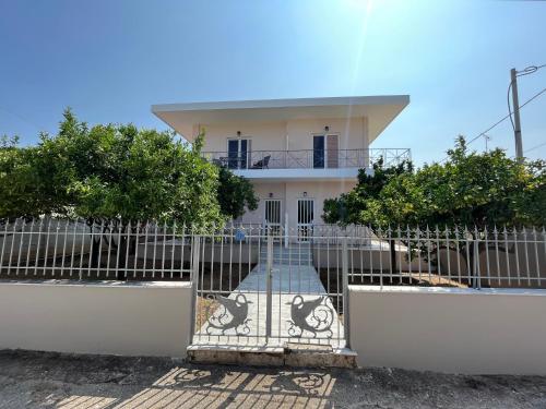 a gate in front of a white house at Koulouras Holiday Apartments in Nikolaíika