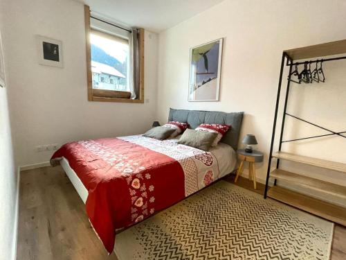 sypialnia z łóżkiem z czerwonym kocem i oknem w obiekcie Le Cowsy w mieście Abondance