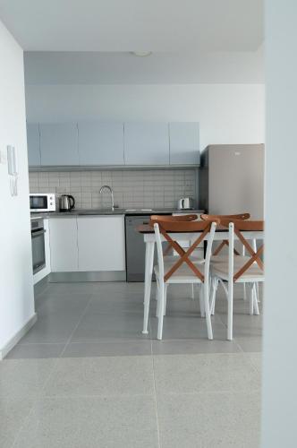 a white kitchen with a wooden table and chairs at Seaview apartments in Ayios Elias