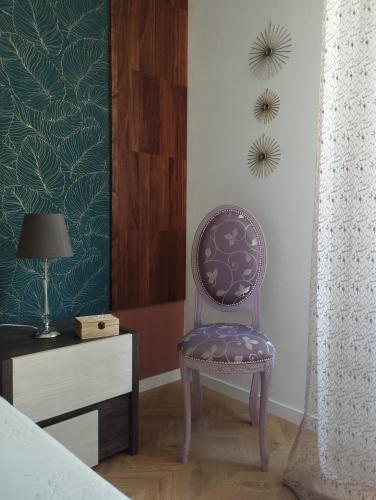a purple chair sitting next to a dresser in a bedroom at La Dama dei Fiori in Vimercate