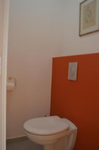 a bathroom with a white toilet and a red wall at VILLA RASOA chambre LIBELLULE in Cap d'Agde