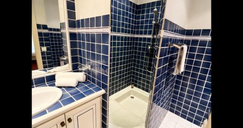a blue tiled bathroom with a sink and a shower at Hôtel l'Arena in Fréjus