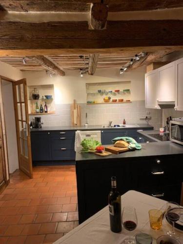 - une cuisine avec des placards bleus et une table avec une bouteille de vin dans l'établissement Charming village house with roof top terrace!, à Thèzan-lès-Béziers