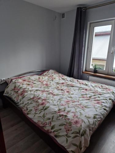 - un lit avec une couette à fleurs dans une chambre dans l'établissement Apartament na Gerberów, à Lądek-Zdrój