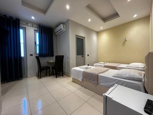 um quarto de hotel com duas camas e uma mesa e cadeiras em HOTEL SARDA em Vau i Dejës