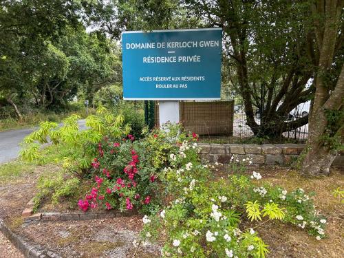 a sign in a garden with flowers in front of it at Résidence l’Esprit de la mer in Combrit