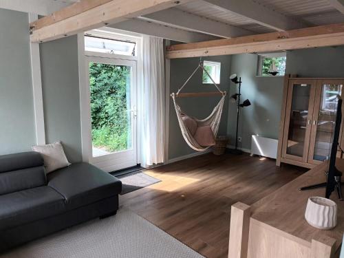 een woonkamer met een bank en een hangmat bij 'Vakantiehuisje Natuurlijk! - nabij molen, meer, strand & stad' in Hoorn