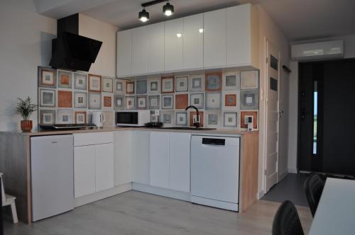 una cocina con armarios blancos y una pared de cuadros. en Apartament 4 Pory Roku, en Darłowo