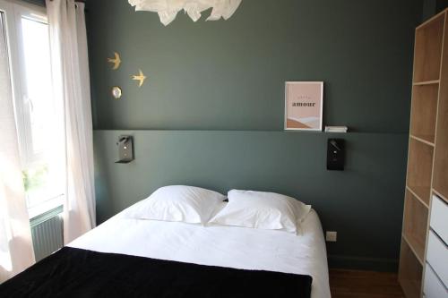 - une chambre avec un lit blanc et un mur bleu dans l'établissement Maisonnette Au 15, à Auxerre