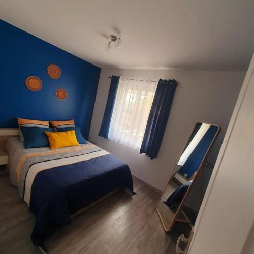 a bedroom with a bed and a blue wall at Joli haut de villa 3 chambres climatisé avec jacuzzi in Marignane