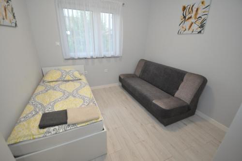 a bedroom with a bed and a couch and a chair at APARTAMENTY POD ŻAGLAMI MIELENKO in Mielenko