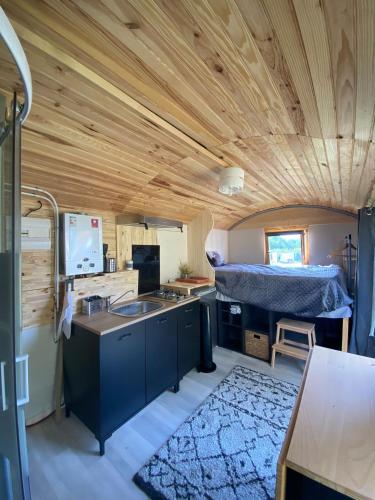 a room with a kitchen and a bed in a trailer at Roulotte goûteux de nature in Saint-Barthélemy
