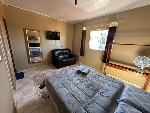 a bedroom with a bed and a leather chair at Flats Paraíso Dos Ipês in Alto Paraíso de Goiás