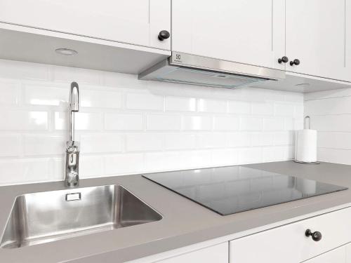 uma cozinha com um lavatório de aço inoxidável e armários brancos em Holiday home Sälen em Stöten