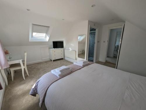 a white bedroom with a large bed and a mirror at Arawak in Kent