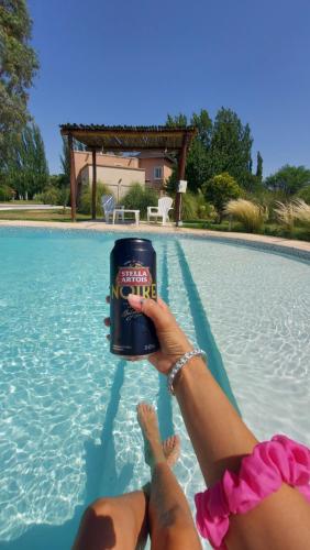 a person holding a can of beer in the water at Cabañas y Habitaciones Terra Nostra Complejo in General Alvear